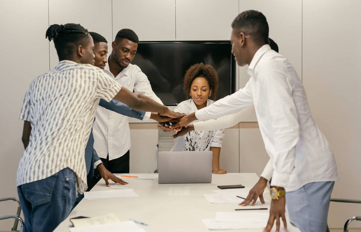 Une équipe réunie autour d'une table de travail, dossiers et portable ouverts.