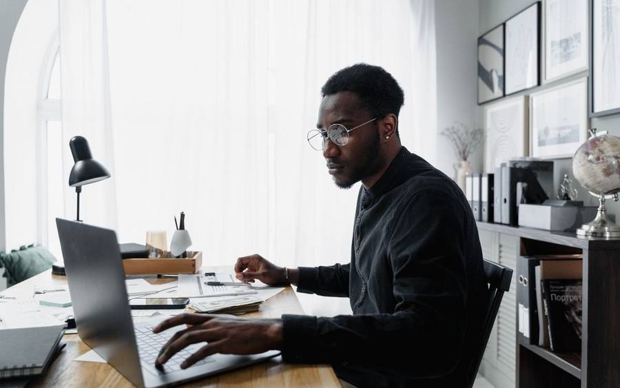 Un technicien assis à un bureau, portable ouvert, en pleine intervention.